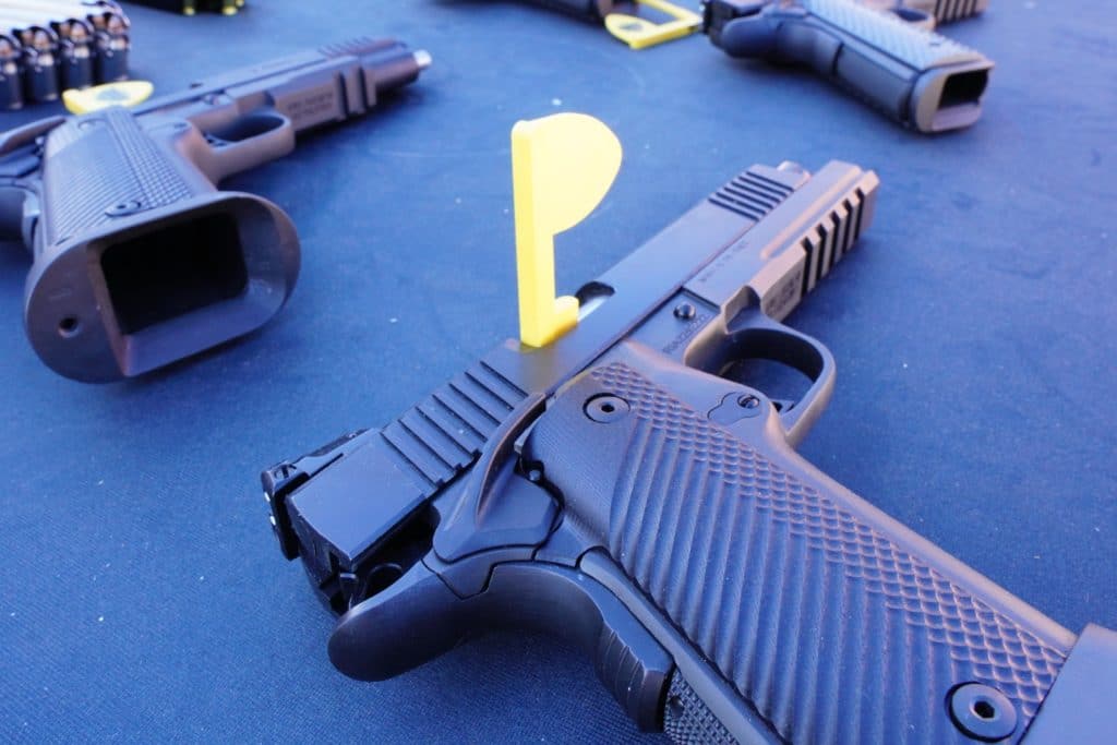 Unloaded handguns sit on a table alongside ammunition