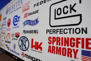 A collection of gun company logos appear on the side of a truck at SHOT Show 2022's range day