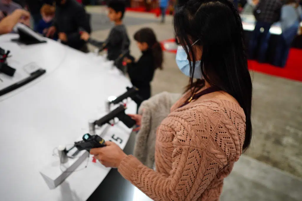 A woman examines a handgun at a display during the 2022 NRA Great American Outdoor Show