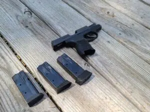 A Sig Sauer P365 and three magazines on a range bench
