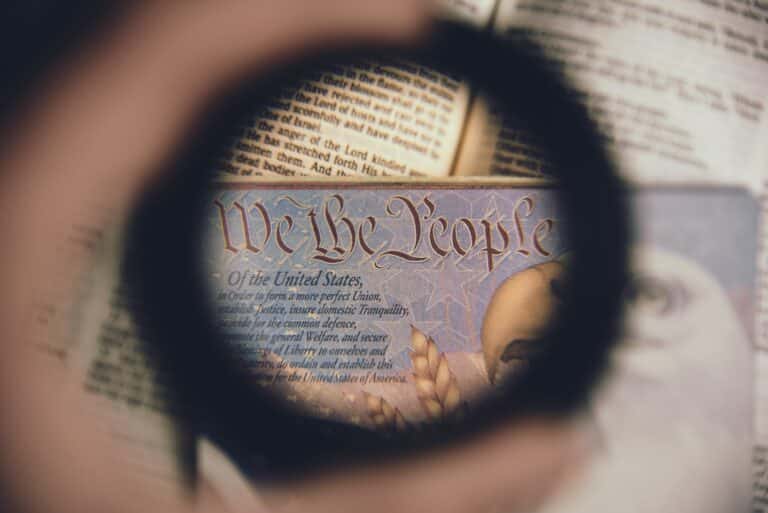 A magnifying glass hovers over the phrase We The People