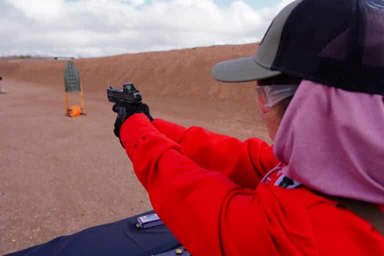 A woman aims a handgun downrange at the 2023 SHOT SHOW