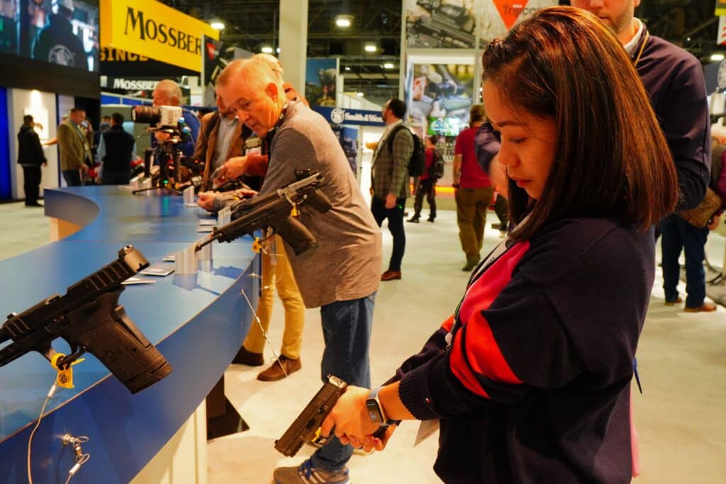 A woman inspects a handgun at the 2023 NRA Annual Meeting