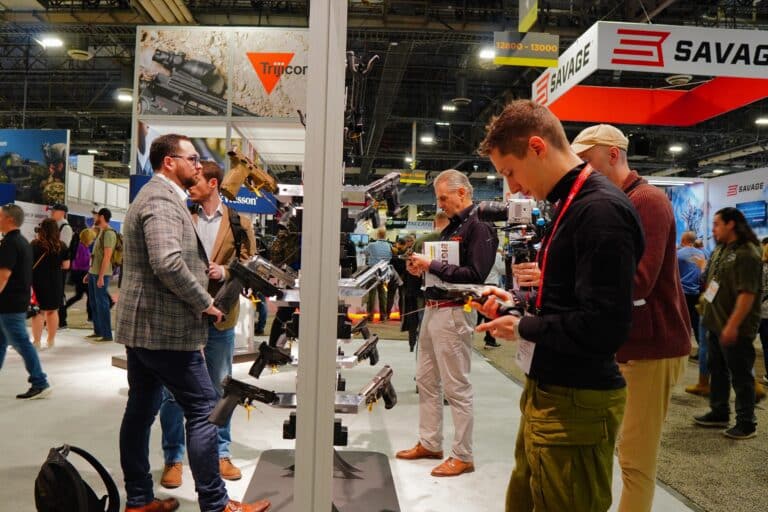 Attendees look over the latest gun models on display at Shot Show 2023