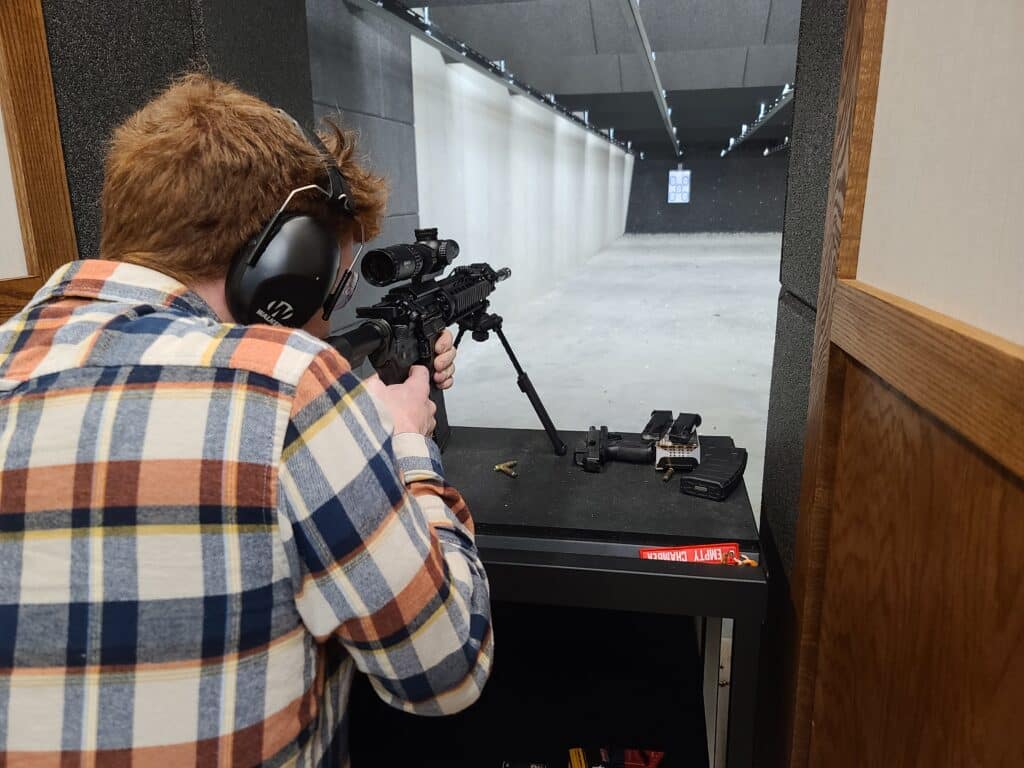 A shooter takes aim at a paper target with an AR-15 at a gun range during April 2023