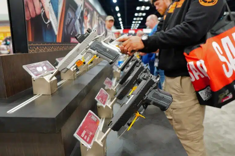 A man handles a pistol at a booth during the 2023 NRA Annual Meeting