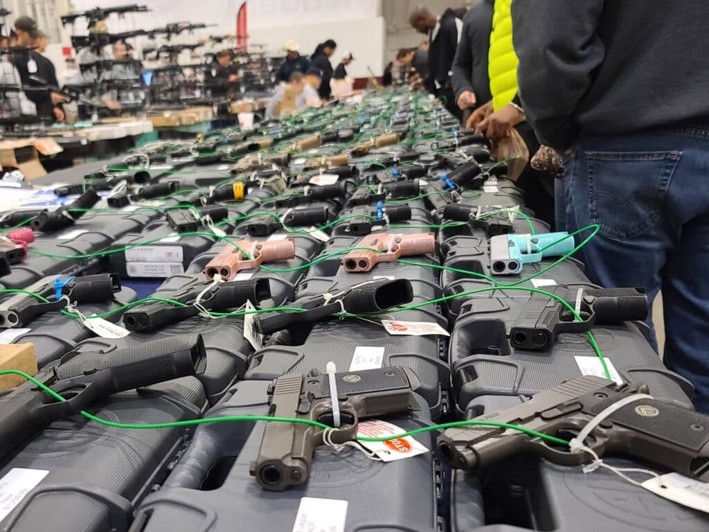 Customers examine handguns at a 2023 gun show
