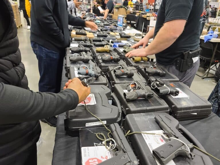 Customers handle some pistols at a gun show booth in December 2023