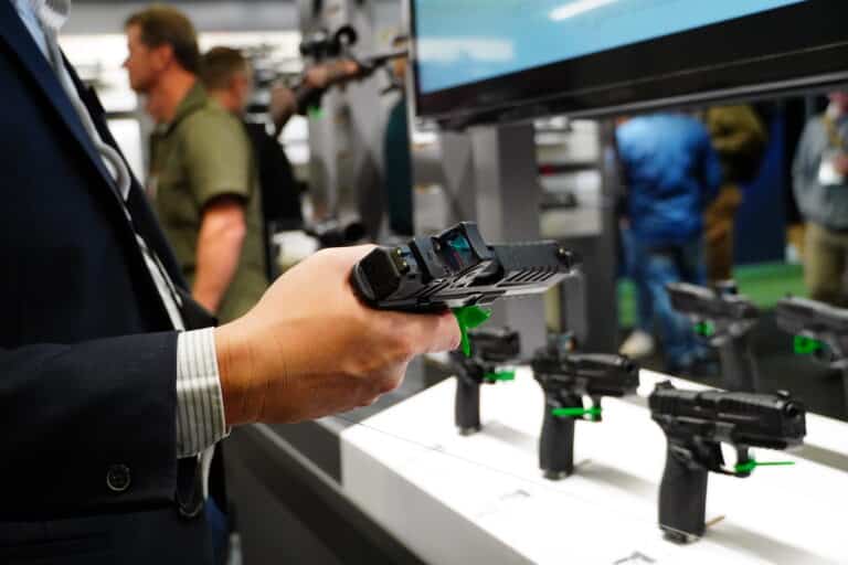 An attendee examines a pistol at the 2024 SHOT Show